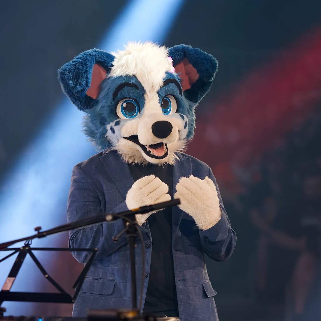 Little Alpha Pup performing on stage in a blue and white fursuit under stage lights